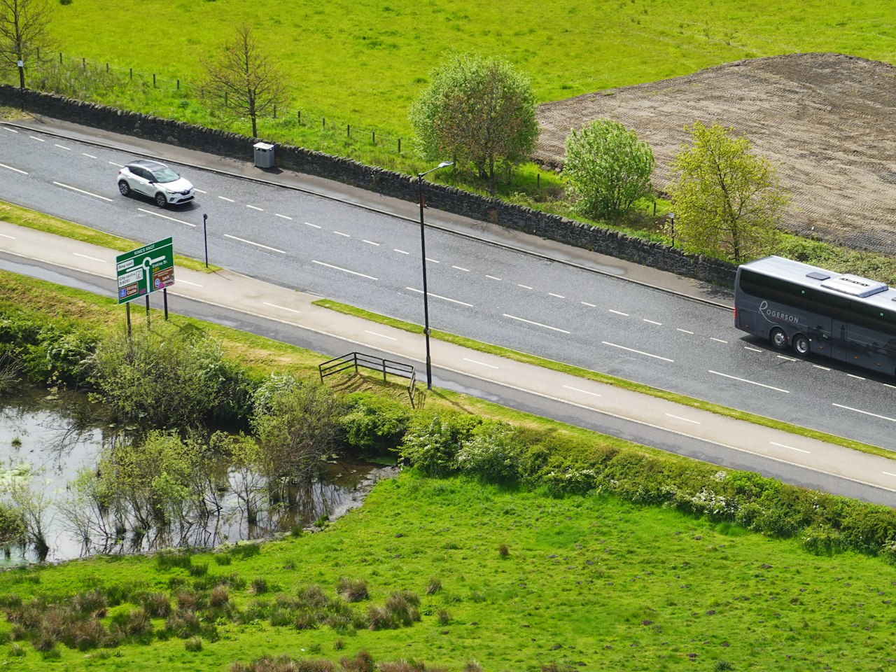 A touring coach on an open road through green countryside