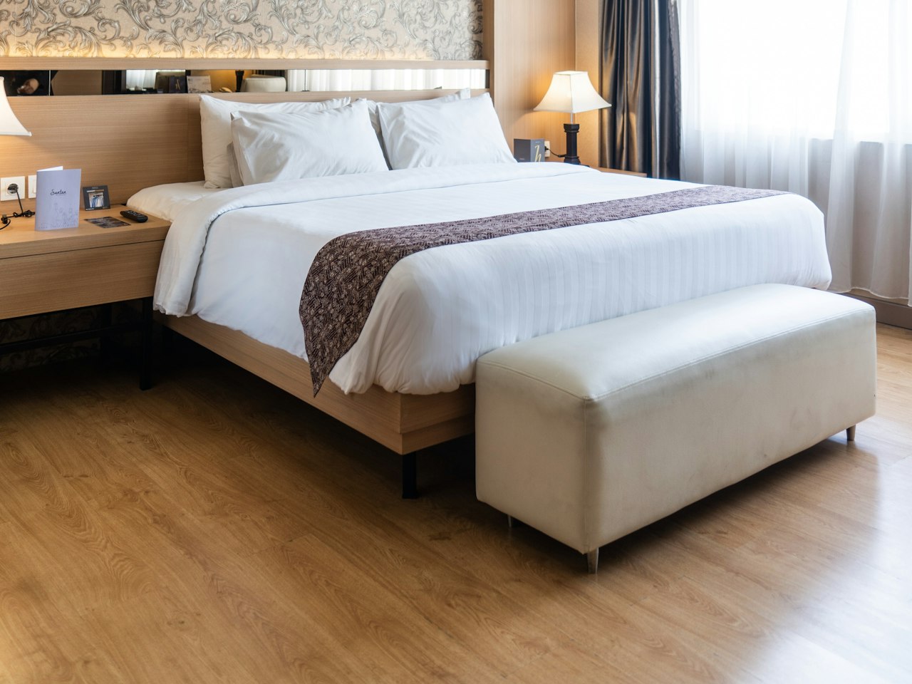 A bright hotel room with a made bed beside a window