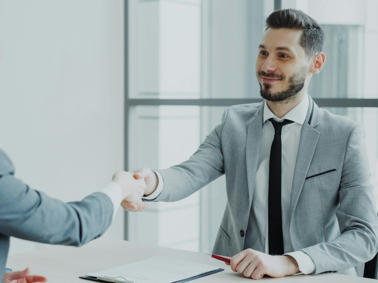 Two travel professionals shaking hands across a desk